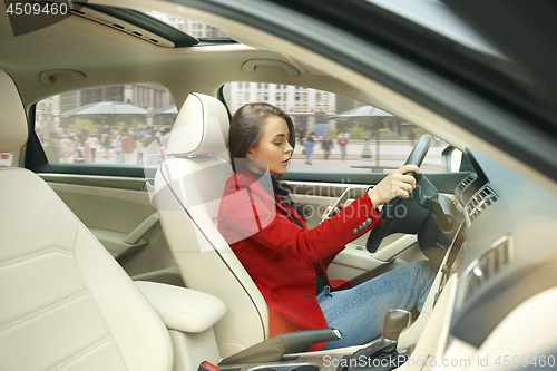 Image of Driving around city. Young attractive woman driving a car