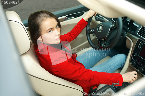 Image of Driving around city. Young attractive woman driving a car