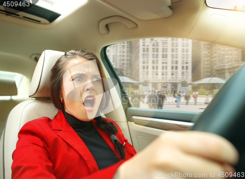 Image of Driving around city. Young attractive woman driving a car