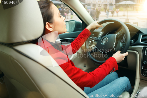 Image of Driving around city. Young attractive woman driving a car