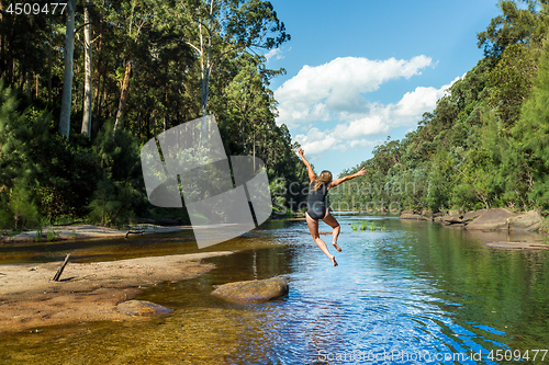 Image of Active Aussie woman jumping into river remote bushland