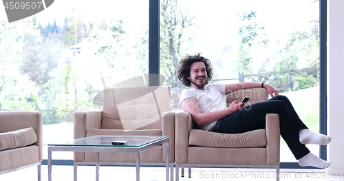 Image of young man using a mobile phone  at home