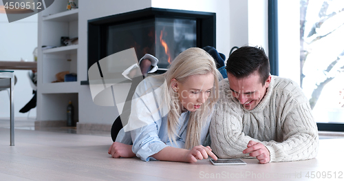 Image of Young Couple using digital tablet on the floor