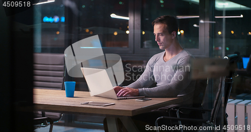 Image of man working on laptop in dark office