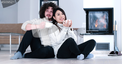 Image of multiethnic romantic couple  in front of fireplace