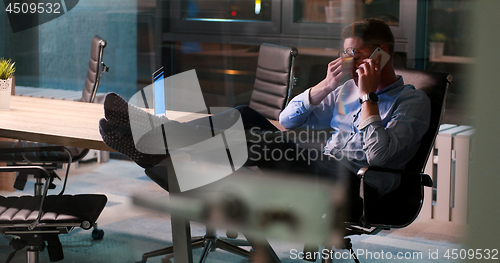 Image of businessman sitting with legs on desk at office