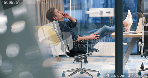 Image of businessman sitting with legs on desk