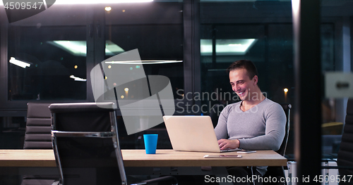 Image of man working on laptop in dark office