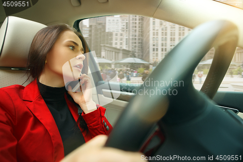 Image of Driving around city. Young attractive woman driving a car