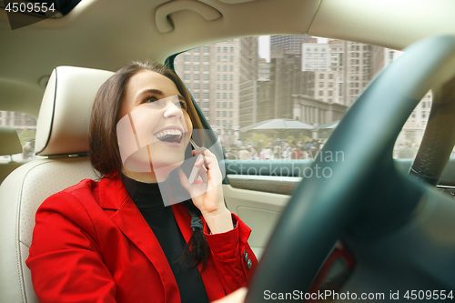 Image of Driving around city. Young attractive woman driving a car