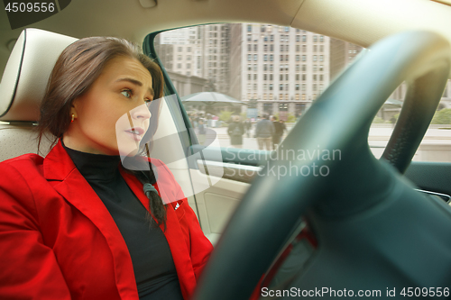 Image of Driving around city. Young attractive woman driving a car