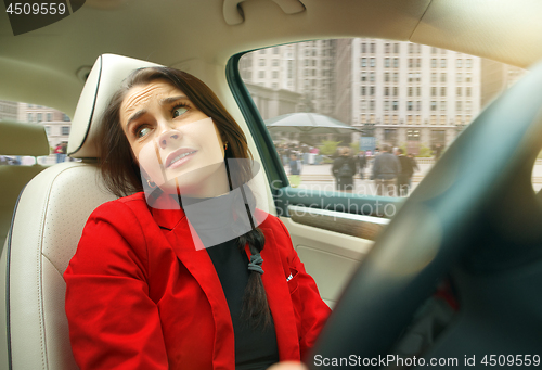 Image of Driving around city. Young attractive woman driving a car