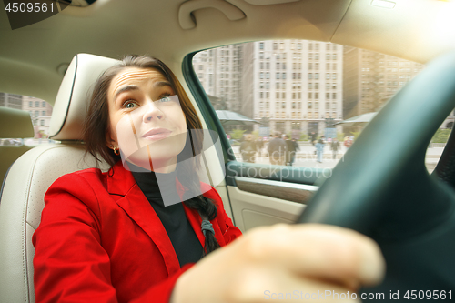 Image of Driving around city. Young attractive woman driving a car