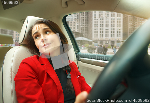 Image of Driving around city. Young attractive woman driving a car