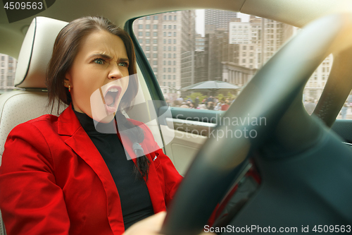 Image of Driving around city. Young attractive woman driving a car