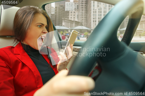 Image of Driving around city. Young attractive woman driving a car