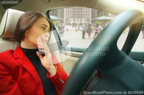 Image of Driving around city. Young attractive woman driving a car