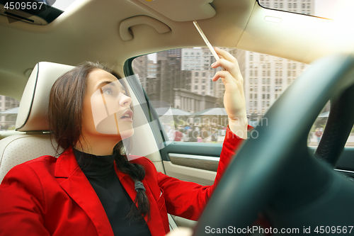 Image of Driving around city. Young attractive woman driving a car