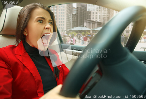 Image of Driving around city. Young attractive woman driving a car