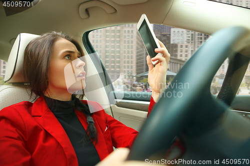 Image of Driving around city. Young attractive woman driving a car