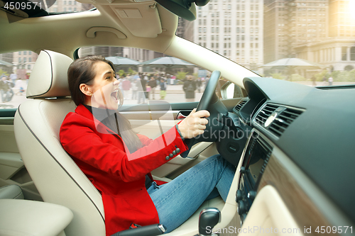 Image of Driving around city. Young attractive woman driving a car