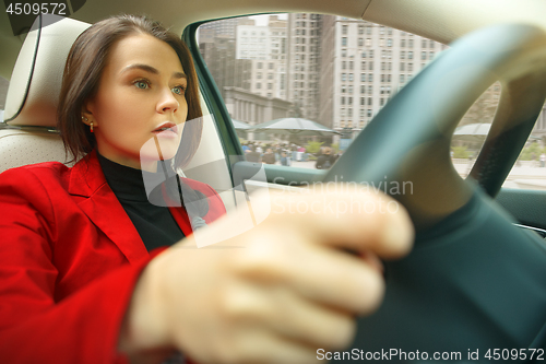 Image of Driving around city. Young attractive woman driving a car