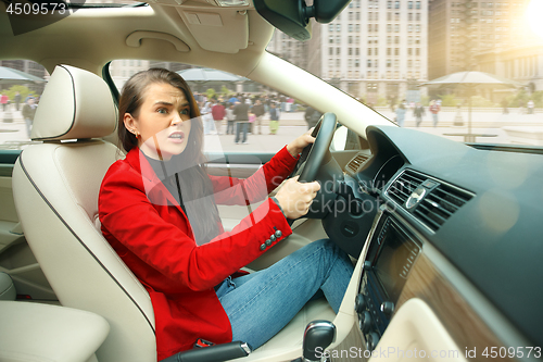 Image of Driving around city. Young attractive woman driving a car