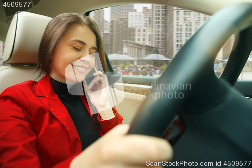 Image of Driving around city. Young attractive woman driving a car