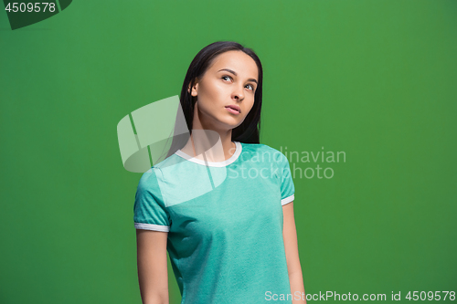 Image of Let me think. Doubtful pensive woman with thoughtful expression making choice against grreen background