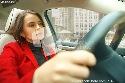 Image of Driving around city. Young attractive woman driving a car