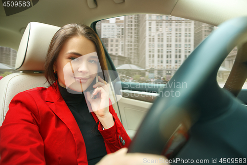 Image of Driving around city. Young attractive woman driving a car