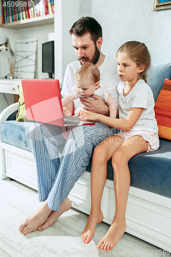 Image of Proud father holding his baby daughters at home