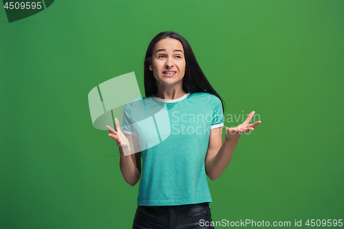 Image of Beautiful female half-length portrait isolated on green studio backgroud. The young emotional surprised woman