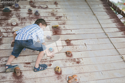 Image of little boy make climbing in the adventure park.