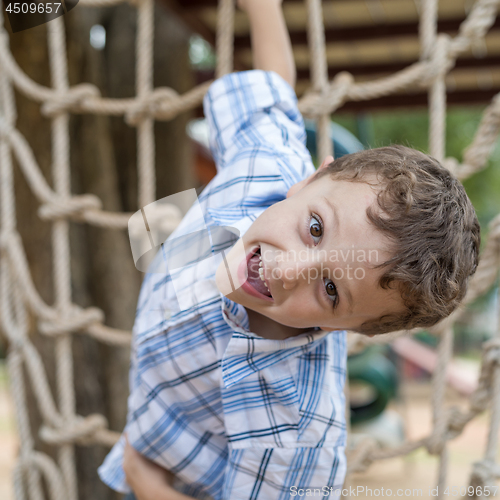 Image of little boy climbing a rock wall outdoor.