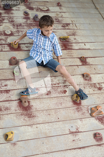 Image of little boy climbing a rock wall outdoor.