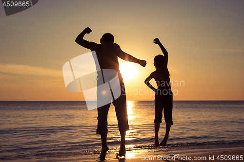 Image of Father and son  playing on the beach at the sunset time.