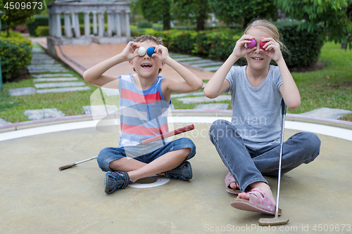 Image of Happy brother and sister playing mini golf 