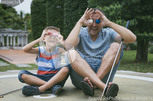 Image of Happy father and  little son playing mini golf.