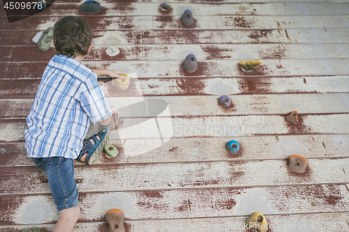 Image of little boy climbing a rock wall outdoor.