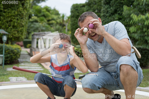 Image of Happy father and  little son playing mini golf.