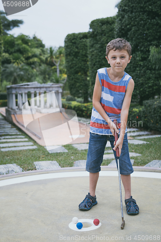 Image of Happy little boy playing mini golf playing mini golf