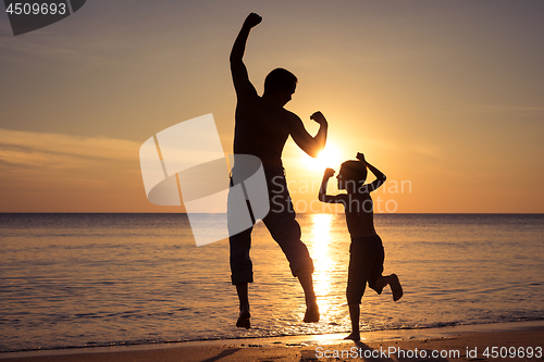 Image of Father and son  playing on the beach at the sunset time.