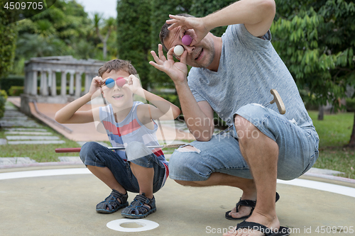 Image of Happy father and  little son playing mini golf.