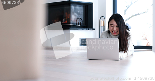 Image of Asian woman using laptop on floor