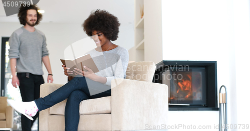 Image of multiethnic couple hugging in front of fireplace