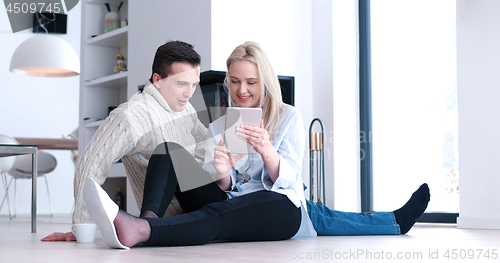 Image of Young Couple using digital tablet on the floor