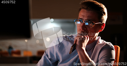 Image of man working on computer in dark office