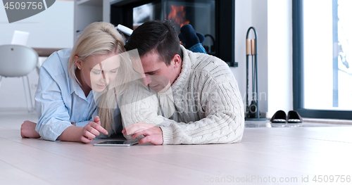 Image of Young Couple using digital tablet on the floor