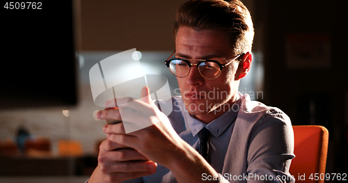 Image of man using mobile phone in dark office